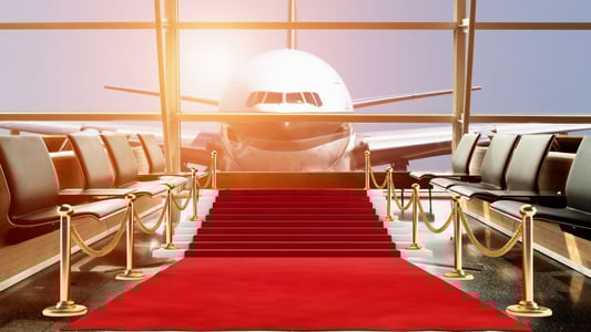 An airplane pulling up to an airport lounge where a red carpet has been rolled out. 