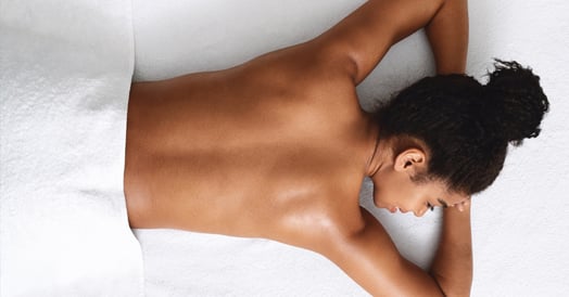 A woman lies face-down on a massage table with her back exposed.