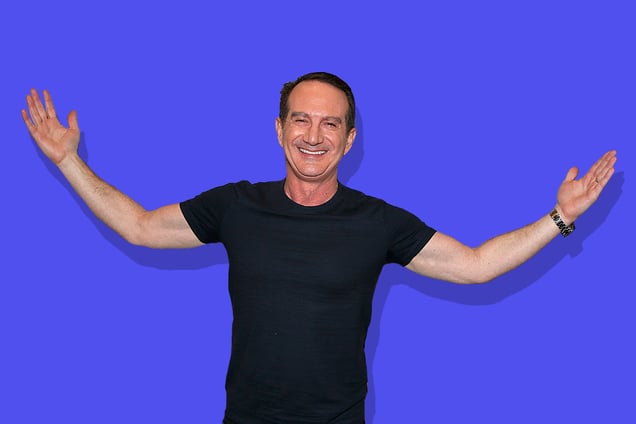 David Bach holding up his hands on a blue backdrop