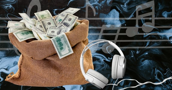 A bag of money next to a pair of white headphones.