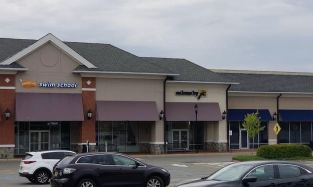 A photo of a Goldfish Swim School storefront within a strip mall, alongside a "Salons by JC" and other businesses.